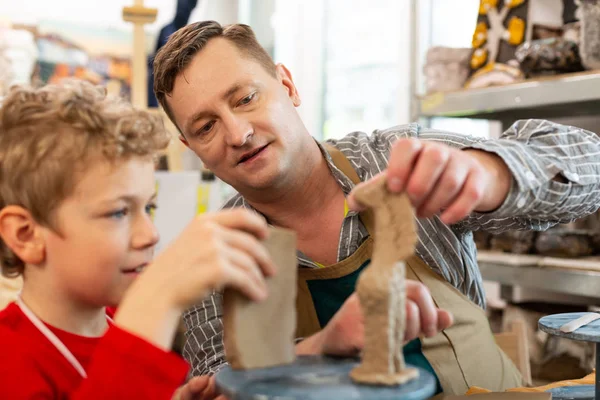 Profesor de arte ayudando a su estudiante a esculpir figuras de arcilla — Foto de Stock