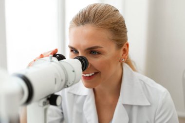 Klinikte çalışırken saçları bağlı olan mavi gözlü gülümseyen hoş bayan