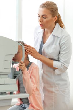 Nazik ciddi göz doktoru genç hastanın pozisyonunu düzeltiyor