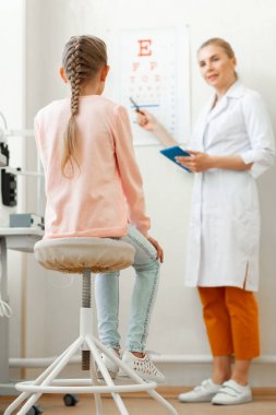 Beyaz üniformalı özenli profesyonel oculist hastanın durumunu kontrol