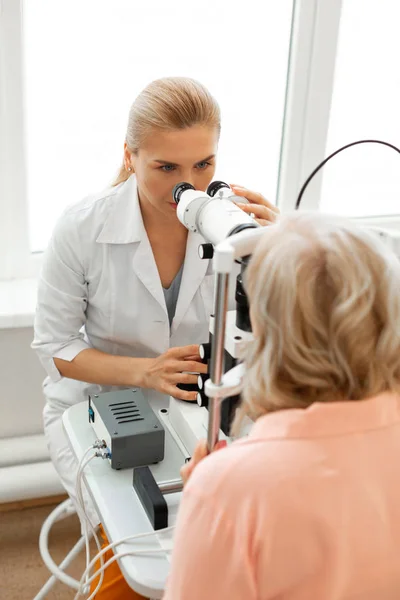 Uppmärksam läkare med bundet blonda hår ser i kikare — Stockfoto