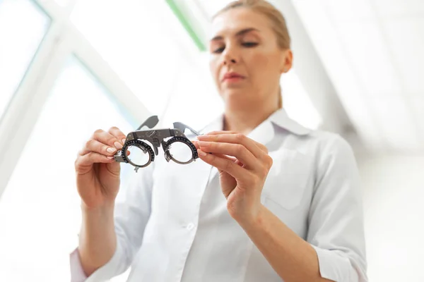 Médico rubio serio en uniforme blanco llevando gafas para medir —  Fotos de Stock