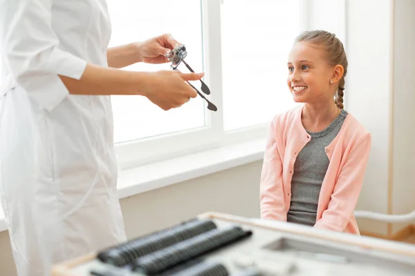 Sorrindo menina bonita com olhos azuis pacientemente sentado no armário médico — Fotografia de Stock