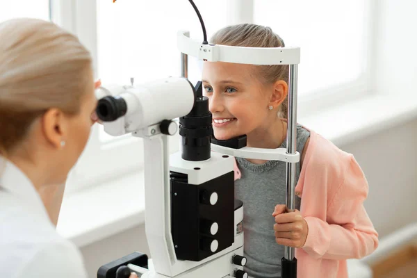 Pretty good-looking little girl placing her head on a black stand