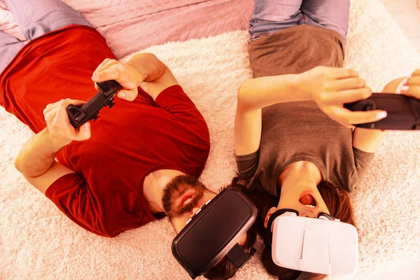 Young couple laying on the bed and playing virtual reality