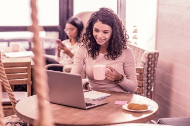 Kafeterya laptop ile otururken onu ödev yapıyor çekici kıvırcık öğrenci