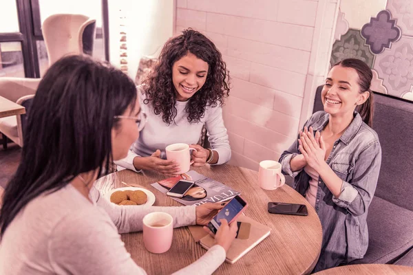 Hermosas mujeres se sienten alegres después de comprobar el pronóstico del tiempo en el teléfono inteligente — Foto de Stock