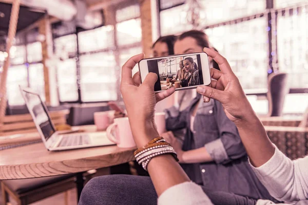 Kvinna klädd i snygga arm band gör foto av hennes vänner på sin smartphone — Stockfoto