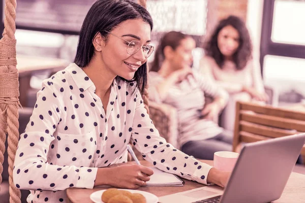 Strahlende Frau mit gefleckter Bluse, die auf ihren Laptop schaut und Nachrichten liest — Stockfoto