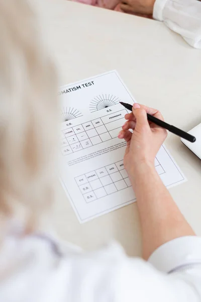 Educated doctor sitting at her cabinet and filling papers — Stock Photo, Image