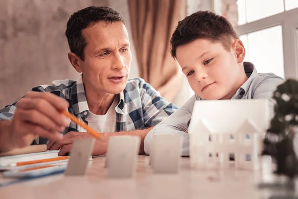 Colegial de ojos oscuros y su padre modelo de construcción de casa separada — Foto de Stock