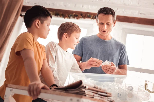 Padre vistiendo camisa azul diciendo a sus hijos acerca de la clasificación de residuos — Foto de Stock