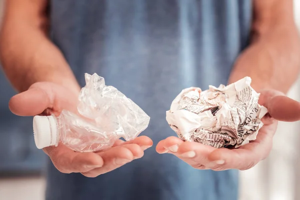 Mann mit blauem Hemd hält Plastik und Papier in der Hand — Stockfoto