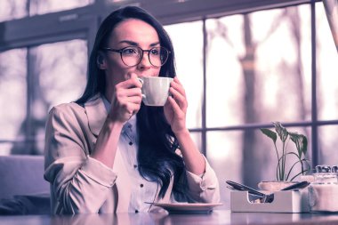 İnanılmaz bir tat. Kahve bir yudum alırken bir fincan tutan güzel genç kadın