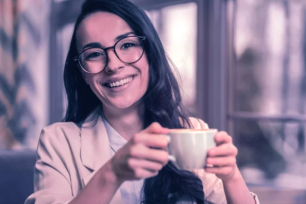 Coffee place. Cheerful delighted woman smiling while visiting cafeteria