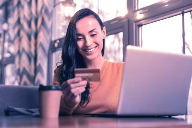 Yeni teknolojiler. İnternet üzerinden ödeme yaparken kredi kartına bakan güzel mutlu kadın