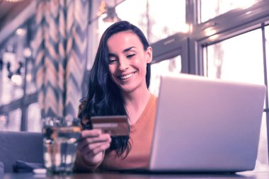 Online ödemeler. Online ödeme yaparken kredi kartı verilerine bakan neşeli mutlu kadın
