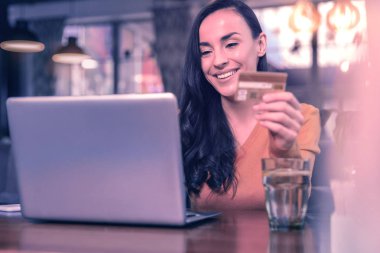 İnternet alışverişi. Online alışveriş yaparken dizüstü bilgisayar önünde oturan pozitif neşeli kadın