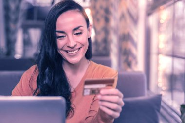 Online alışveriş. Memnun olumlu kadın online alışveriş yaparken kredi kartı bakarak