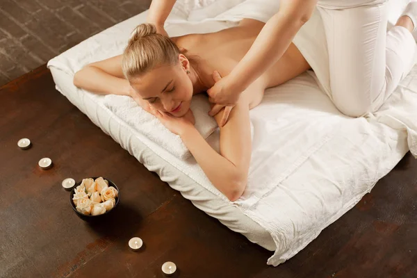 Calme jeune femme avec un chignon de cheveux blonds en cours de séance de massage — Photo