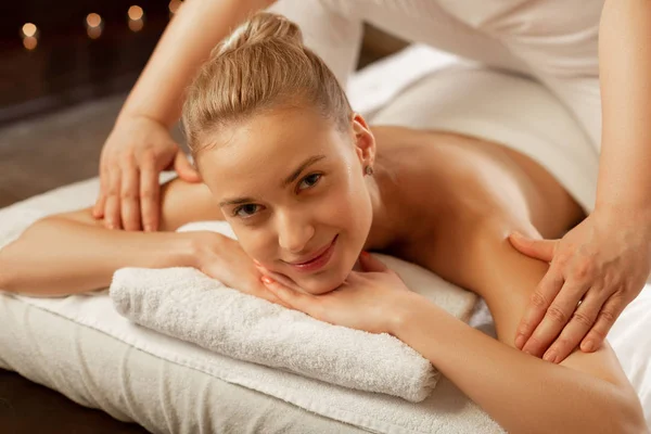 Sorrindo menina nua de boa aparência deitada em toalhas brancas enquanto mestre de massagem — Fotografia de Stock