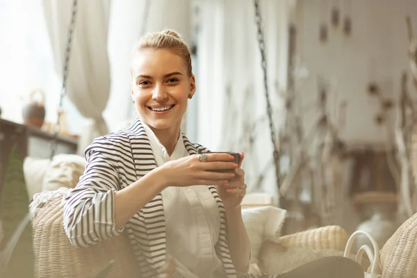 Nieuwsgierig mooie vrouw in wit shirt dragen Cup met thee — Stockfoto