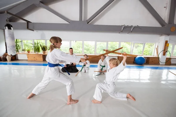 Girl wearing white kimono attacking boy with jo — Stock Photo, Image