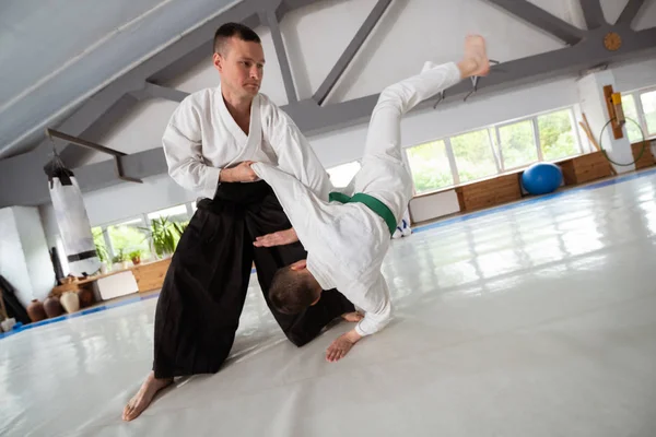 Aikido trainer practicing throw with pupil in white kimono — Stock Photo, Image