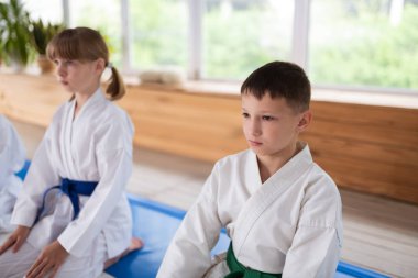 Arkadaşının yanında oturan beyaz kimono giyen koyu saçlı çocuk