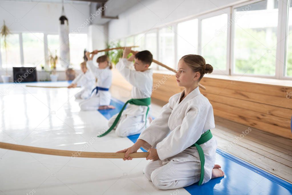 Girls and boys wearing white kimono learning aikido movements