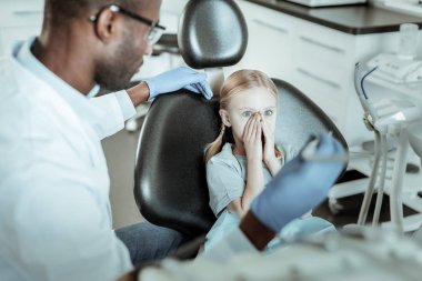 Küçük mavi gözlü kız diş hekimi ekipmanları korkuyor