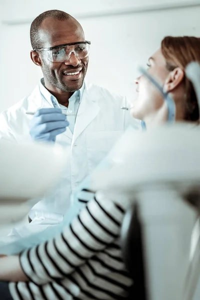 Professionell mörkhyade tandläkare frågar sin patient om att öppna munnen — Stockfoto