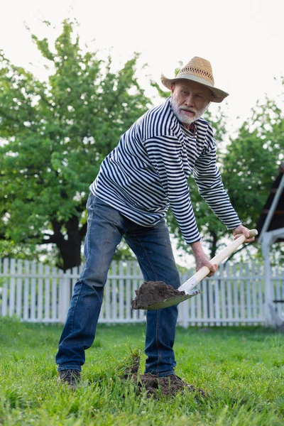 Gepensioneerde man graven grond in de buurt van zijn huisje huis — Stockfoto