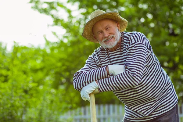 Hombre sonriendo de pie cerca de la pala después de trabajar en el jardín — Foto de Stock