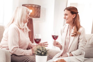 Pembe li iki bayan bir kadeh kırmızı şarap içiyor.