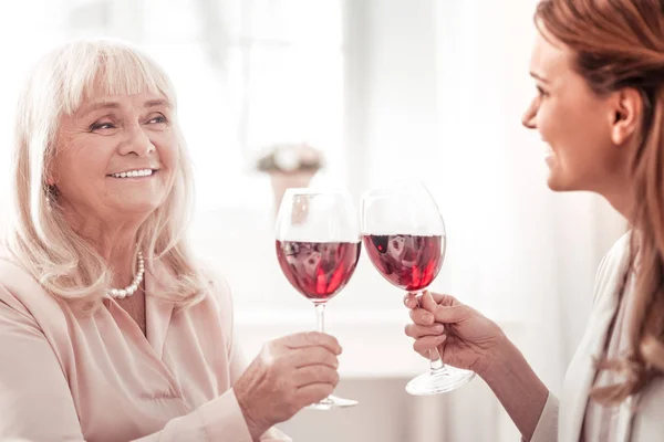 Koyu saçlı gülümseyen kadın annesi ile bir kadeh şarap sahip — Stok fotoğraf