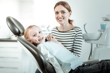 Gülümseyen anne ve dişçi randevusu olan neşeli kızı