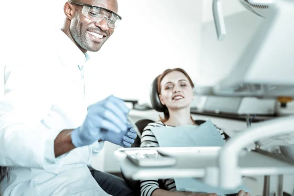 Positiv strahlender Arzt, der seine sterilisierten Werkzeuge vom Tisch nimmt — Stockfoto