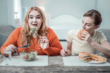 Aç genç kadın burger parçası ısırma