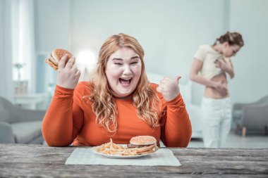 Neşeli uzun saçlı kadın kişi arkadaşını işaret