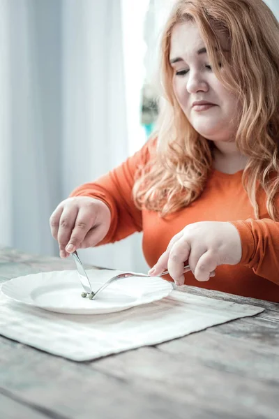 Skeptic young woman looking at her plate — Stock Photo, Image