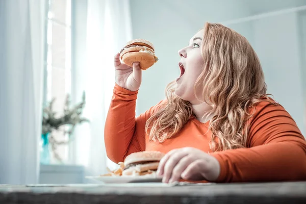 Hungry blonde plump woman eating unhealthy food — Stock Photo, Image