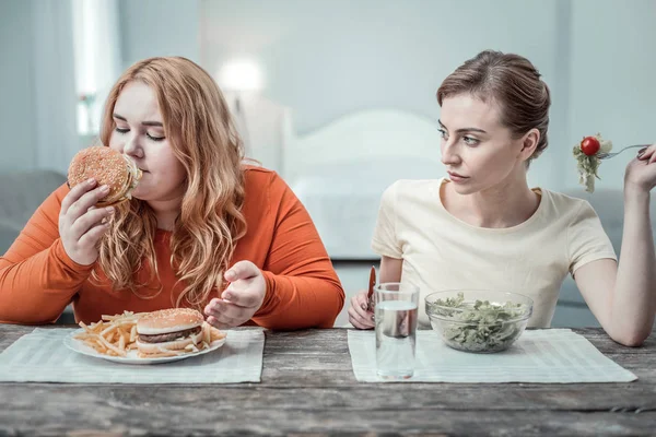 Enigmatical övervikt kvinnlig person luktar välsmakande Burger — Stockfoto