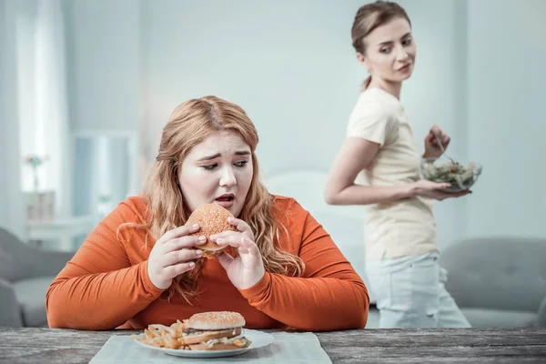 Zaniepokojony longhaired dziewczyna będzie jeść Burger — Zdjęcie stockowe