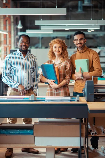 Fröhliche Verlagsmitarbeiter lächeln, während sie Bücher in der Hand halten — Stockfoto