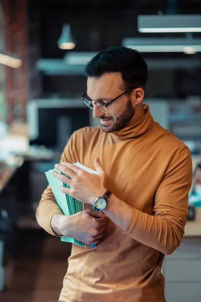 Man counting colorful notebooks working in publishing company