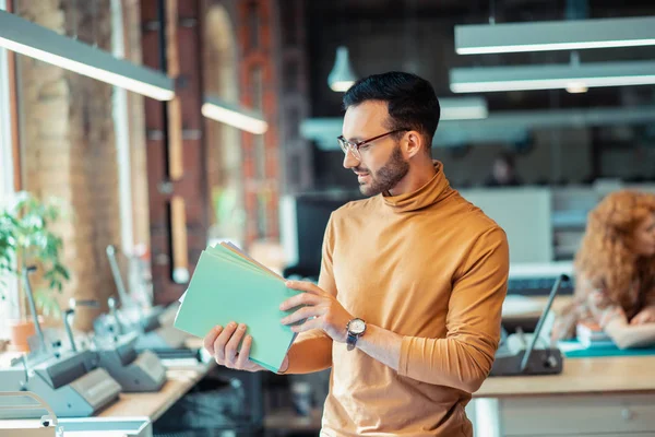 Hombre barbudo sosteniendo cuadernos que trabajan en la editorial — Foto de Stock