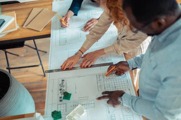 Mannen en vrouwen voelen zich betrokken bij het afwerken van schetsen voor project — Stockfoto