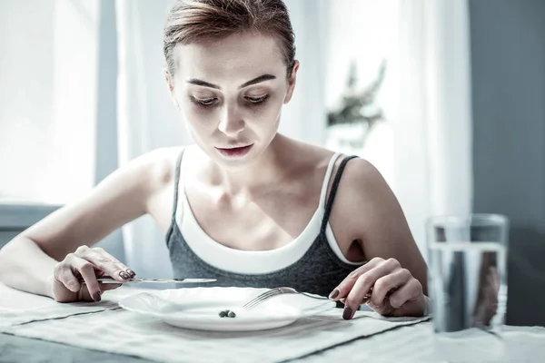 Внимательная молодая женщина смотрит на свою тарелку — стоковое фото