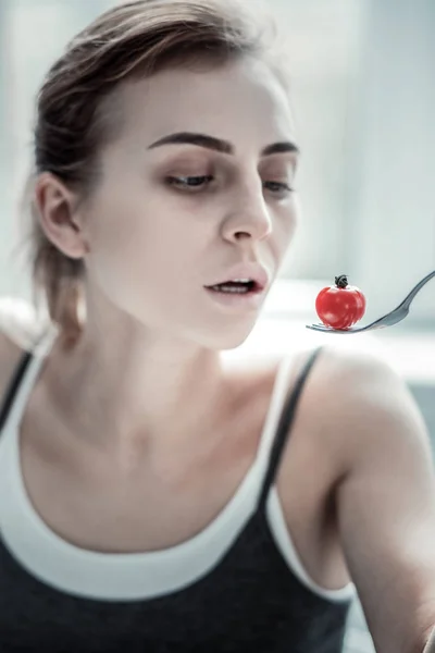 Jovem mulher concentrada comendo legumes pequenos — Fotografia de Stock